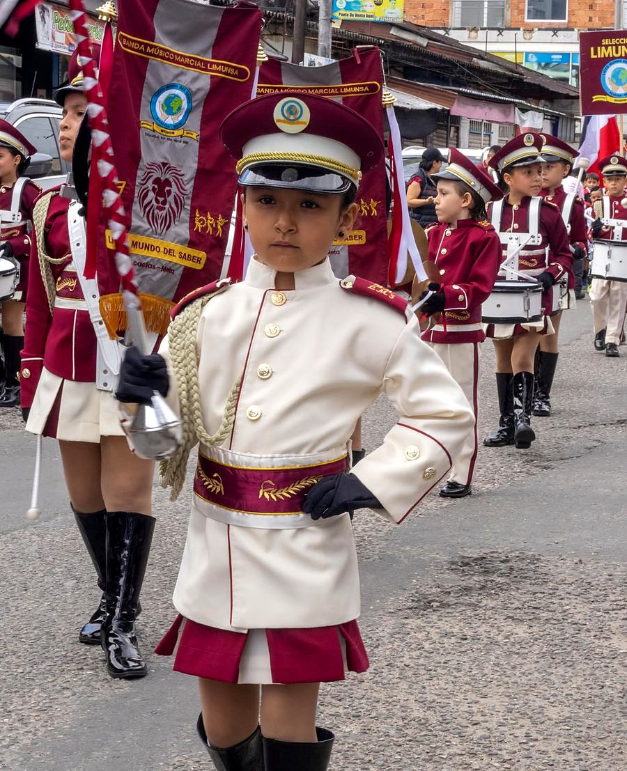 Estudiante de la banda marcial del colegio desfilando con su uniforme blanco y vinotinto