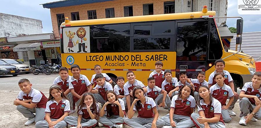 Estudiantes de quinto grado junto al bus del colegio